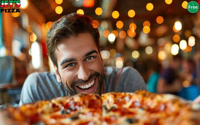 A happy customer smiling while eating a Jet's Pizza